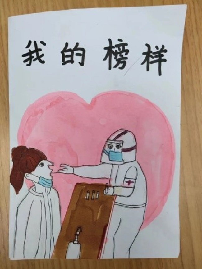 图为一位社区小朋友为医务人员送上感谢信及绘画作品